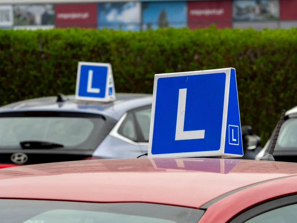 Lesauto met L-bord op het dak bij een rijschool in Nederland